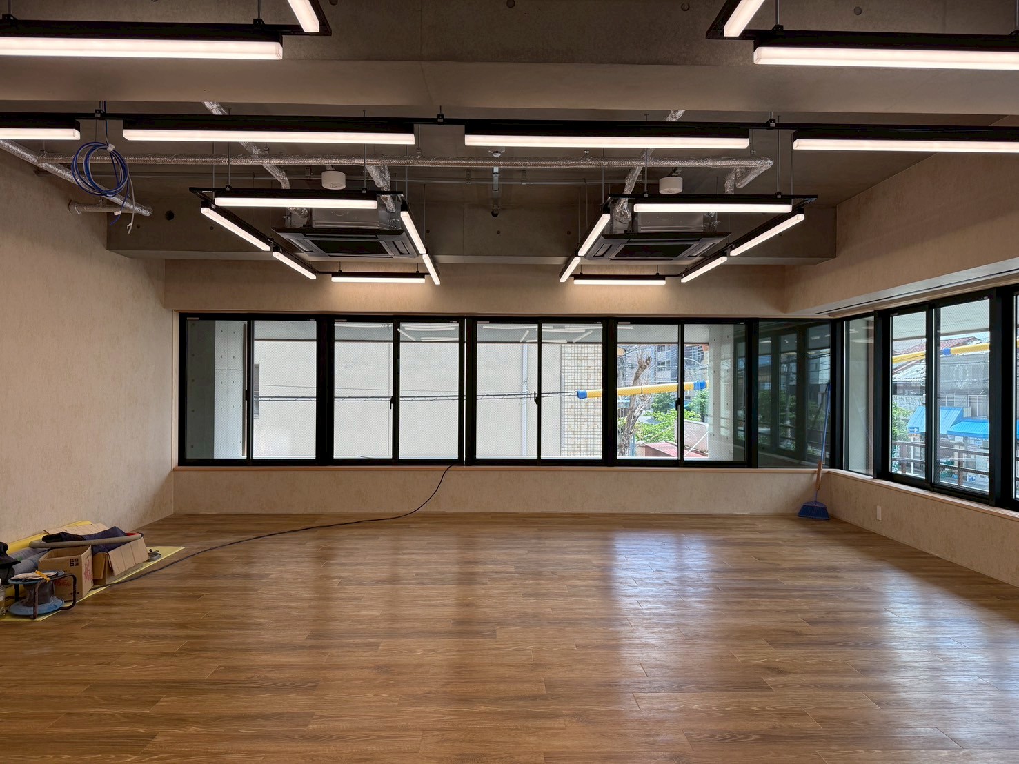 日本語: L型窓を持つ執務スペースの内観｜English: Interior of L-shaped office space with natural light and open layout