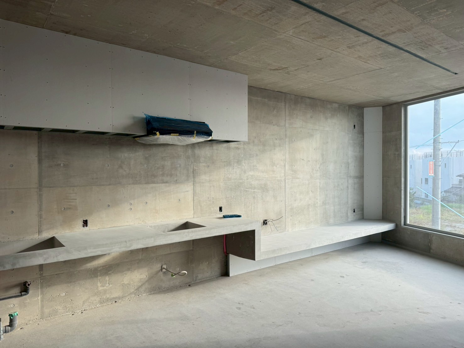 日本語: 収納・デスク・キッチンを一体化したコンクリート家具｜English: Concrete furniture integrating storage, desk, and kitchen functions